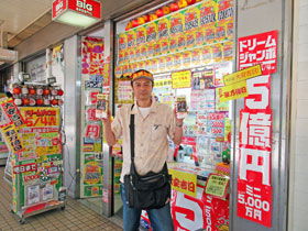 大阪駅前第2ビルラッキーセンター高橋さん窓口の前で今日買った宝くじを持って記念撮影